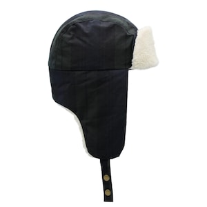 May include: A black trapper hat with a quilted texture and white faux fur lining the ear flaps. The hat has a chin strap with two gold-colored snap closures. The hat is designed to provide warmth and protection from the cold.