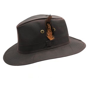Op de afbeelding: Een bruine wollen fedora hoed met een brede rand en een klein bruin veren accent.