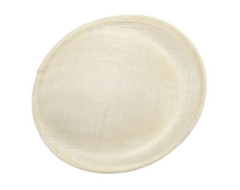 May include: A cream-colored, oval-shaped hat base with a woven texture. The hat base has a rounded edge and is made of a light, natural material. The hat base is suitable for millinery projects.
