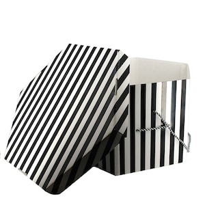 May include: A black and white striped gift box with a lid slightly ajar. The box has a rope handle and is set against a white background. The stripes are diagonal on the lid and vertical on the box.