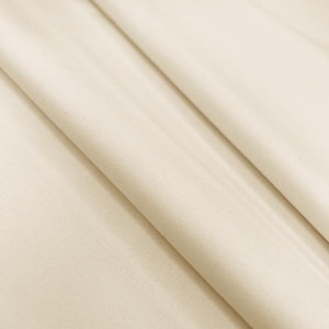 May include: Close-up of folded, off-white fabric. The material has a subtle texture and drapes in soft folds, creating shadows and highlights. The colour is a warm, neutral tone, suitable for various applications.