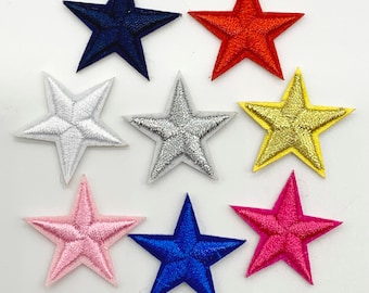 Könnte beinhalten: Acht gestickte Filzsterne in verschiedenen Farben, darunter Rot, Blau, Gold, Silber, Rosa und Weiß. Die Sterne sind alle gleich groß und haben die gleiche Form und sind in einem zufälligen Muster angeordnet.