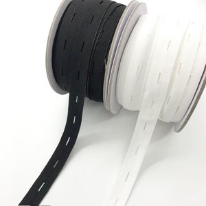 May include: Two spools of elastic with buttonholes. One spool is black and the other is white.