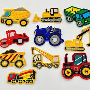 May include: A selection of colourful embroidered patches depicting construction vehicles. The patches include a yellow dumper truck, a blue tractor, a green lorry, a red steamroller, a yellow excavator, a yellow crane, a red tractor, and a yellow cement mixer.
