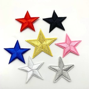 May include: Seven embroidered iron-on patches in the shape of stars. The stars are in the colors red, black, gold, pink, blue, silver, and white.
