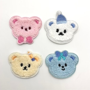 May include: Four embroidered iron-on patches featuring cute cartoon bears with different coloured fur and accessories. The bears are wearing a bow, a hat, a bow, and a bow.