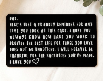 May include: A rectangular black metal wallet card featuring white engraved text that reads: DAD, HERE'S JUST A FRIENDLY REMINDER FOR ANY TIME YOU LOOK AT THIS CARD. I HOPE YOU ALWAYS KNOW HOW HARD YOU WORK TO PROVIDE THE BEST LIFE FOR THOSE YOU LOVE DOES NOT GO UNNOTICED. I WILL FOREVER BE THANKFUL FOR THE SACRIFICES YOU'VE MADE. I LOVE YOU. A small white heart symbol is at the end.
