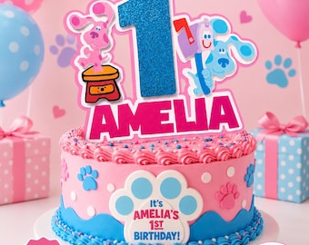 Puede incluir: Un adorno para tarta rosa con un número uno azul brillante, el nombre AMELIA en letras rosas llamativas y personajes de Blue's Clues. El adorno incluye un perro rosa, un perro azul y un buzón, todo sobre una tarta de cumpleaños rosa.