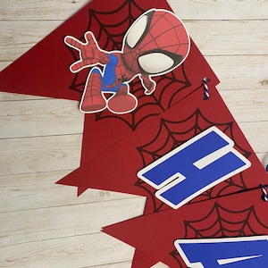 Puede incluir: Bandera roja y azul con un personaje de Spiderman y las letras 'Happy' en azul sobre un fondo rojo con un dise&ntilde;o de telara&ntilde;a negra.