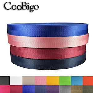 May include: A close-up of five different colors of webbing, including blue, pink, burgundy, navy, and black. The webbing is 25mm wide and has a herringbone pattern. The colors are arranged in a stack, with the blue webbing on top. The image also shows a variety of other colors of webbing, including white, beige, yellow, green, orange, purple, gray, and brown.