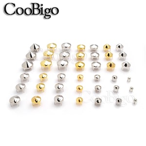 May include: Assortment of silver and gold metal pyramid studs in various sizes. The studs have a flat base and a pointed top.