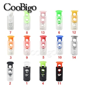 May include: Assortment of 14 plastic toggle clasps in various colours, including black, white, red, orange, green, blue, and silver. Each clasp has a spring mechanism and two holes for attaching to a cord or strap.