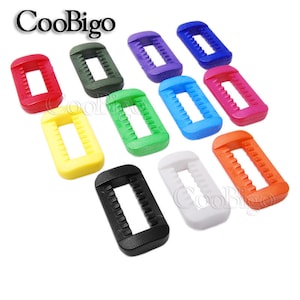 Peut inclure: Assortiment de dix boucles coulissantes en plastique de différentes couleurs, dont rouge, vert, jaune, bleu, violet, orange, noir et blanc. Les boucles sont toutes de la même taille et de la même forme, avec un design rectangulaire et un petit trou au centre.