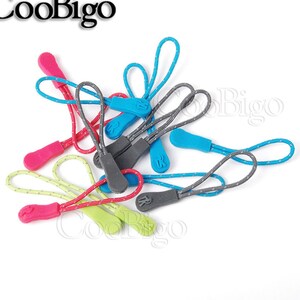 May include: Assortment of colourful zipper pulls with a grey string. The zipper pulls are made of plastic and have a small letter 'R' on them.