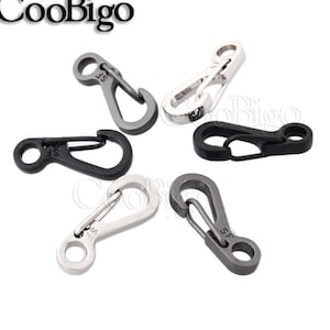 Può includere: Cinque portachiavi in metallo argentato e nero con un moschettone a molla. I portachiavi hanno tutti la stessa forma e dimensione, ma hanno finiture diverse. Alcuni sono argentati, altri sono neri e altri sono una combinazione di entrambi.