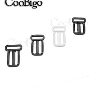 May include: Four plastic slider buckles, two black and two white. The buckles have three slots and are used for adjusting straps.