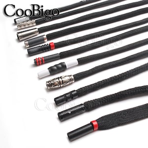 May include: A selection of black cord ends with various metal and plastic tips. The tips include a silver metal tip with a decorative design, a black plastic tip with a red accent, and a silver metal tip engraved with the word "FASHION".