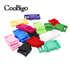 Op de afbeelding: Assortiment van kleurrijke plastic kattenvormige schuifgespen. De gespen zijn in verschillende kleuren, waaronder roze, blauw, groen, rood, geel, paars, wit en zwart.