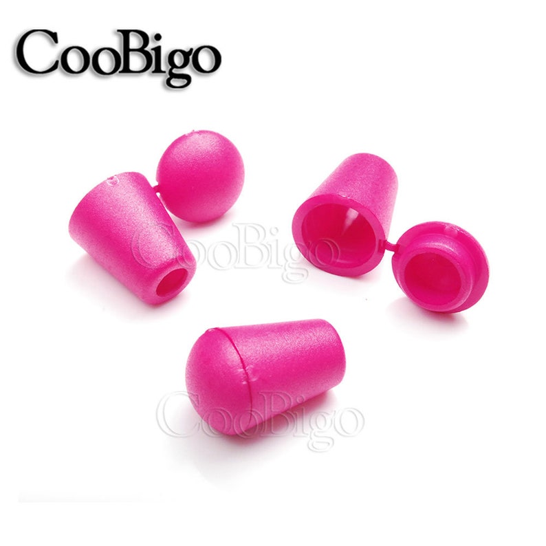 May include: Three pink plastic cord end stoppers. Two of the stoppers are cone shaped with a round top. The third stopper is a cone shape with a rounded end.