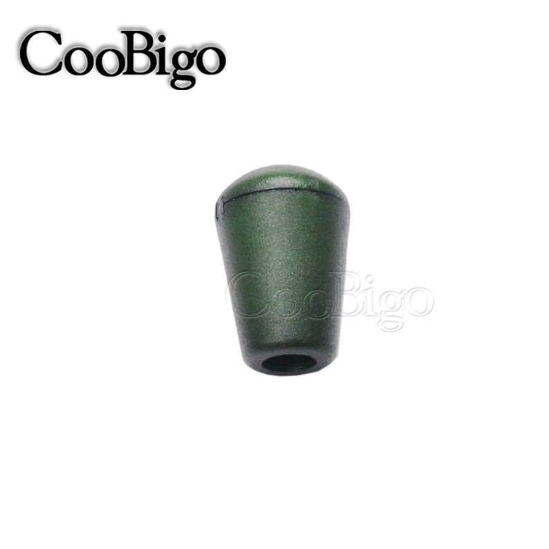 May include: A dark green plastic cord end stop with a smooth, rounded top and a hole in the bottom.