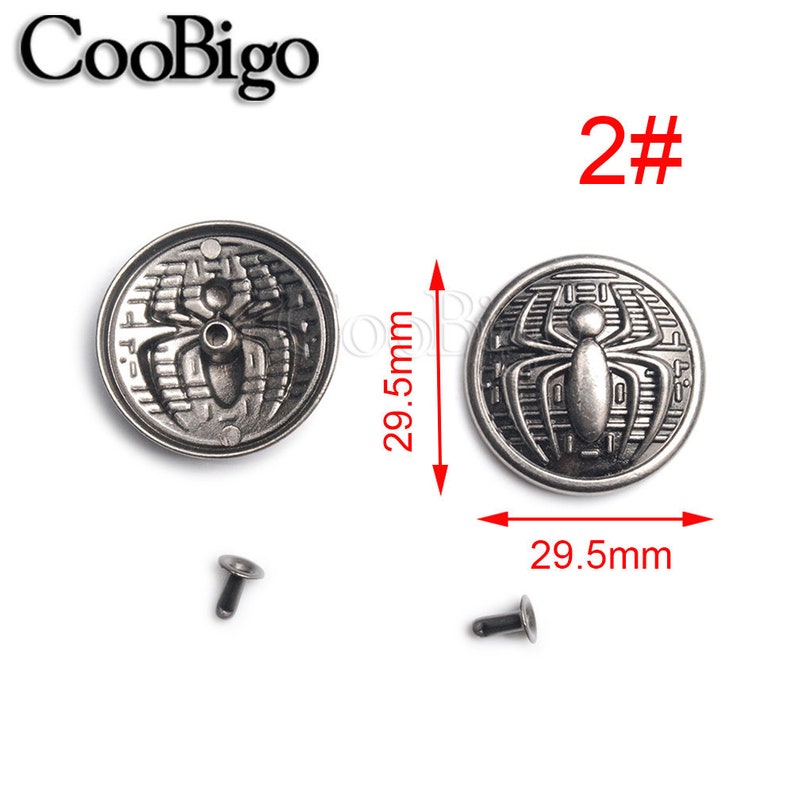 May include: Two silver-toned metal buttons with a spider design. Each button measures 29.5 mm in diameter. The buttons are accompanied by two silver-toned metal rivets.