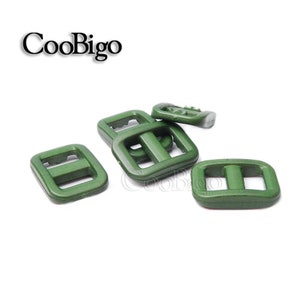 Op de afbeelding: Een set van tien groene plastic schuifgespen. De gespen zijn rechthoekig met een enkele middelste balk. De gespen worden vaak gebruikt voor banden, tassen en andere doe-het-zelfprojecten.