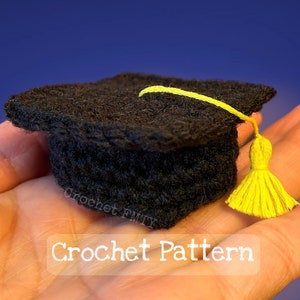 Może przedstawiać: Mały czarny, szydełkowy czepek absolwenta z żółtym frędzlem. Wzór na szydełku.