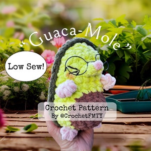 May include: Crochet pattern for a green and brown avocado-shaped mole wearing glasses. The pattern is called "Guaca-Mole" and is described as "Low Sew!" The pattern is by @CrochetFMT.
