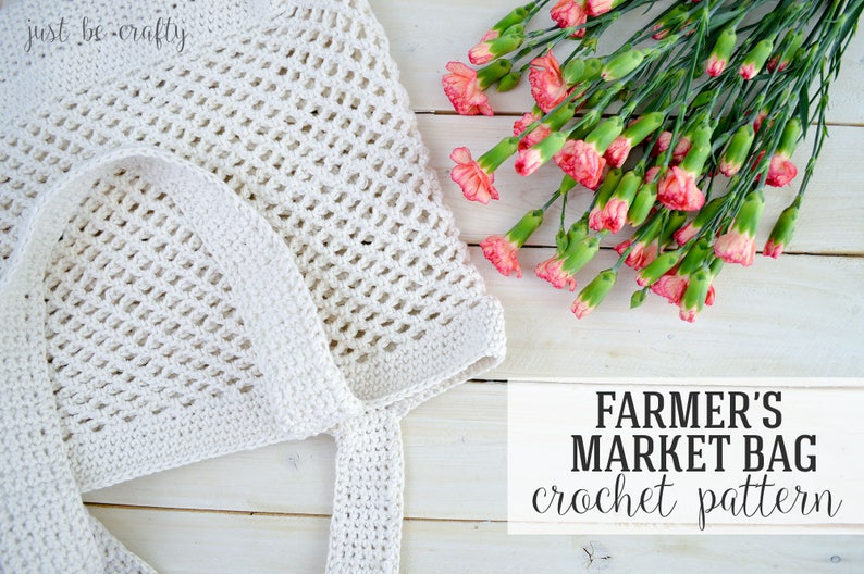 May include: White crochet market bag with a long handle, lying on a white wooden surface. A bouquet of pink carnations is in the upper right corner of the image. The text "FARMER'S MARKET BAG crochet pattern" is at the bottom of the image.