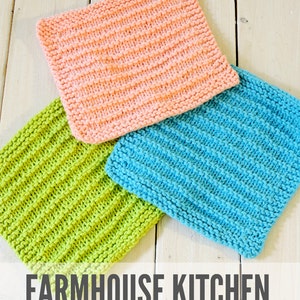 Peut inclure: Trois torchons en tricot de différentes couleurs : rose, vert et bleu. Les torchons sont empilés les uns sur les autres sur une surface en bois blanc. Le texte « FARMHOUSE KITCHEN knitted dishcloth pattern » est imprimé sous les torchons.