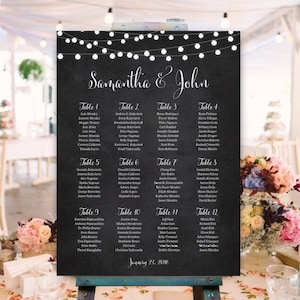 May include: A chalkboard wedding seating chart with a black background and white string lights. The chart lists the names of guests assigned to each table. The text at the top of the chart reads "Samantha & John". The date "January 23, 2016" is written at the bottom of the chart.