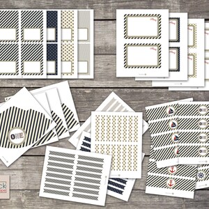 May include: Printable set of nautical themed party decorations. Includes labels, cupcake toppers, and banners in navy blue, white, and gold with red accents. The set features a sailboat, anchor, and steering wheel designs.