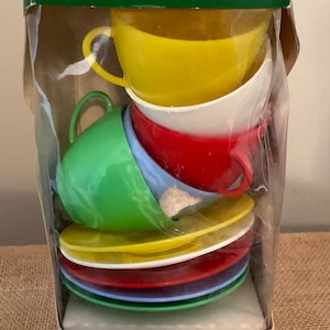 May include: A set of colorful plastic teacups and saucers in a clear plastic package. The box says "A Child Guidance Toy" and "Tipsy Teacups" with the ages 1 to 4.
