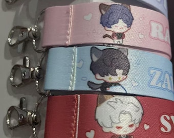 May include: A stack of five lanyards with cartoon cat-eared characters. Each lanyard is a different color: light blue, pink, light blue, red, and orange. Each lanyard has a silver clasp and a printed name.