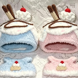 May include: Two handmade crochet pet beds shaped like ice cream sundaes, one blue and one pink, each with a white whipped cream top, a red cherry, and two brown wafer sticks. Two matching smaller hats are also shown.