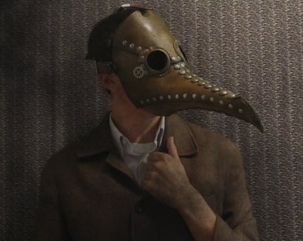May include: A person wearing a brown leather plague doctor mask with metal accents and a brown jacket.