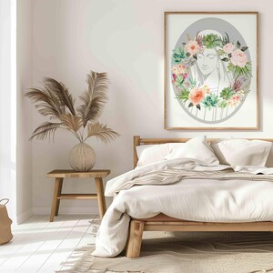 May include: A white bed with a white and brown striped blanket and two white pillows. A framed print of a woman's face surrounded by flowers hangs on the wall above the bed.