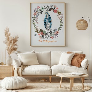 May include: A white framed print with a floral wreath surrounding a depiction of the Virgin Mary. The text "Holy Mother pray for us" is printed below the image.