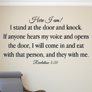 May include: A wall decal featuring a religious quote from Revelation 3:20. The quote reads "Here I am! I stand at the door and knock. If anyone hears my voice and opens the door, I will come in and eat with that person, and they with me. Revelation 3:20". The decal is on a light beige wall in a room with a chair and a door.