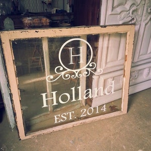 May include: A vintage window pane with a white painted monogram "H" in a decorative circle, the text "Holland" and "EST. 2014" below.