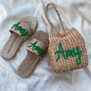 May include: Two pairs of woven straw sandals with green embroidered lettering that says "Amy" and a woven straw tote bag with a green embroidered handle and lettering that says "Amy".