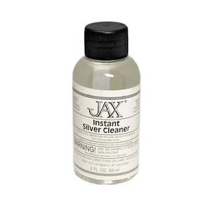 以下が含まれることがあります： 黒いキャップとラベルが付いた透明なプラスチックボトル。ラベルには「JAX Instant Silver Cleaner」と、皮膚刺激の可能性に関する警告が記載されています。ボトルには、59 ml（2 fl oz）の銀磨き剤が入っています。