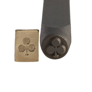 May include: A metal stamp with a club suit design. The stamp is used to create impressions on metal or other materials.