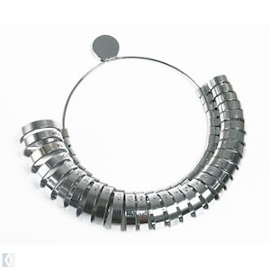 May include: A silver ring sizer with a circular design. The sizer is made of metal and has a series of rings that are numbered from 1 to 30.