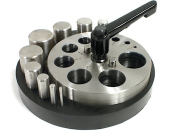 May include: A metal circle cutter tool with a black handle and various sized cylindrical punches. The tool has a silver finish and is set on a black base. The cutting holes are labeled with inch measurements.