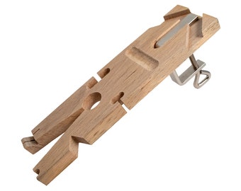 May include: A wooden workbench with a clamp and a variety of cutouts for holding different sized objects. The workbench is made of light brown wood and has a natural finish.