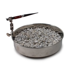 May include: A silver metal dish filled with small white rocks. A silver metal tool with a wooden handle is attached to the side of the dish.
