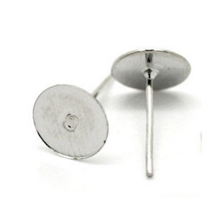 May include: Two silver earring posts with flat round backs. The posts are approximately 1.2 cm long and the backs are about 0.6 cm in diameter.