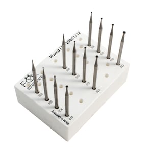 May include: A set of 12 round diamond burrs in a white plastic holder. The burrs are labelled with their sizes, ranging from 0.05 to 0.23 inches. The holder has the text "Round (1 20001/12" and "Made in Germany" printed on it.
