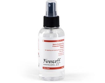 Op de afbeelding: Een heldere spuitfles met een zwarte spuitmond en dop, met het label "Firescoff". Het etiket bevat tekst over nano-keramisch flux voor het repareren en restaureren van fijne sieraden. De fles bevat 120 ml vloeistof.